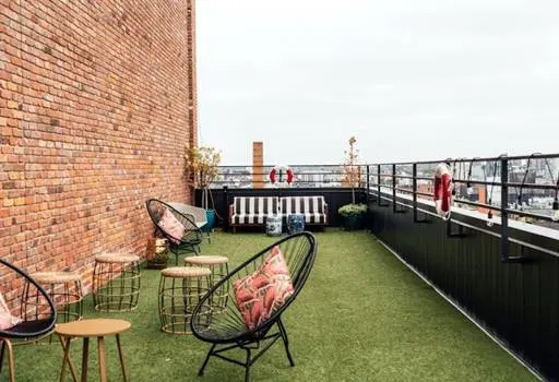 Rooftop seating area with modern furniture and artificial grass turf.